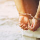 Misdemeanor Convictions - Arrest the offender. Prison male criminal standing in handcuffs with hands behind back.