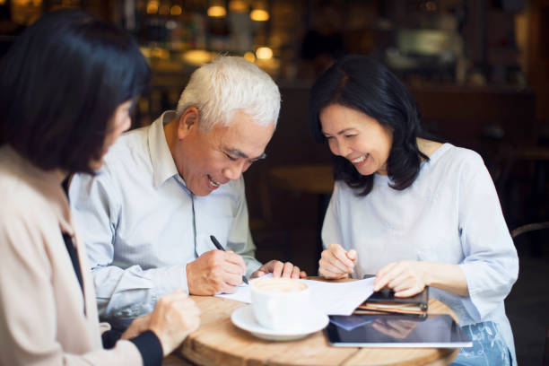 Senior Asian couple signing financial agreement to their financial advisor.