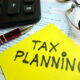 Tax Implications - Tax planning text, 1040 form, pen, calculator and eyeglasses